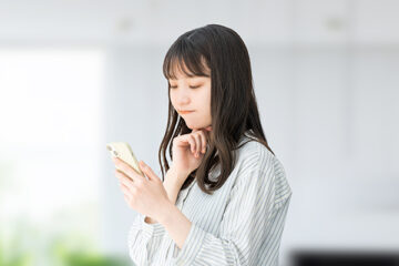 スマホを見て考える女性